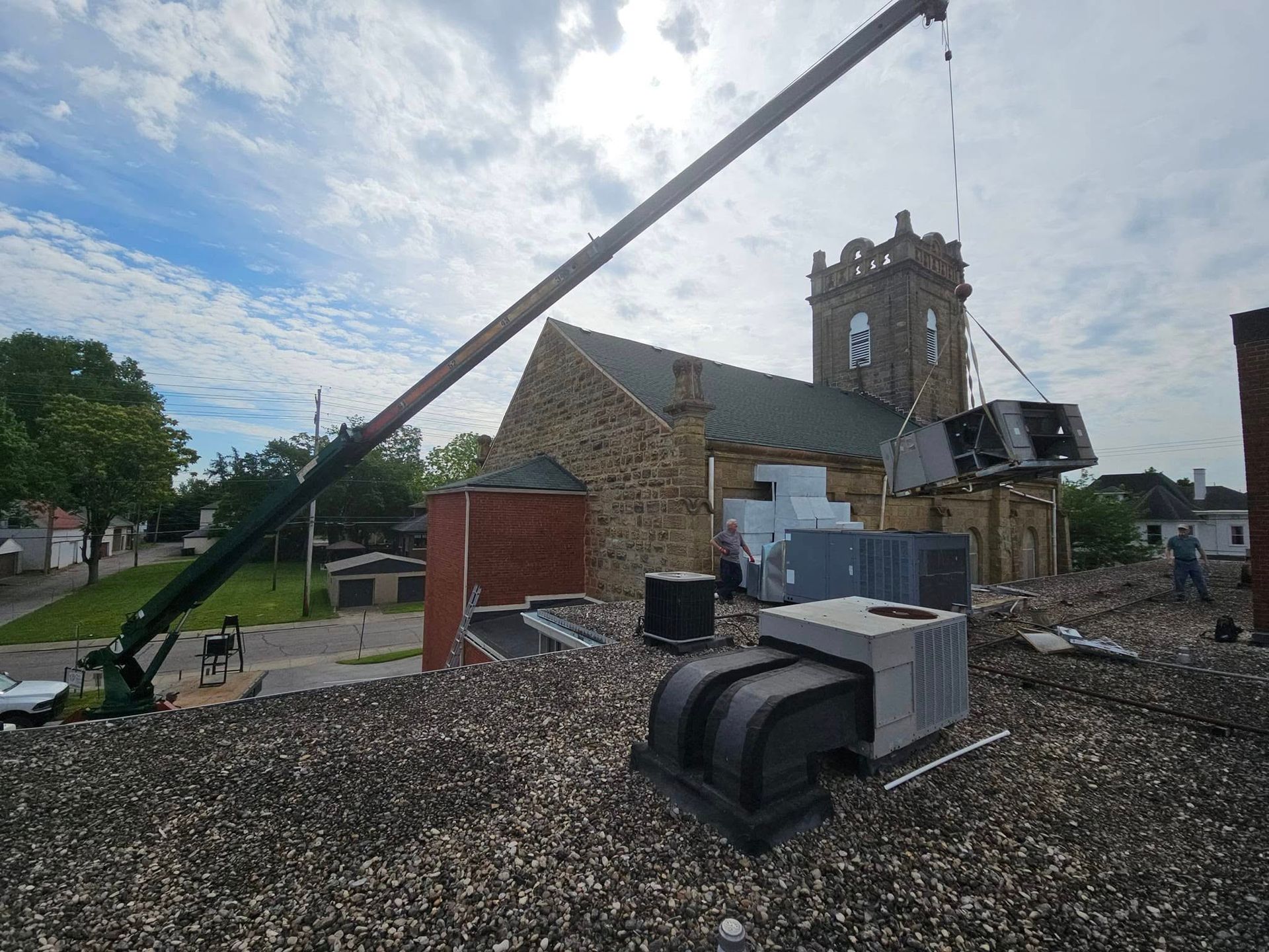 A crane is lifting a machine on top of a building.