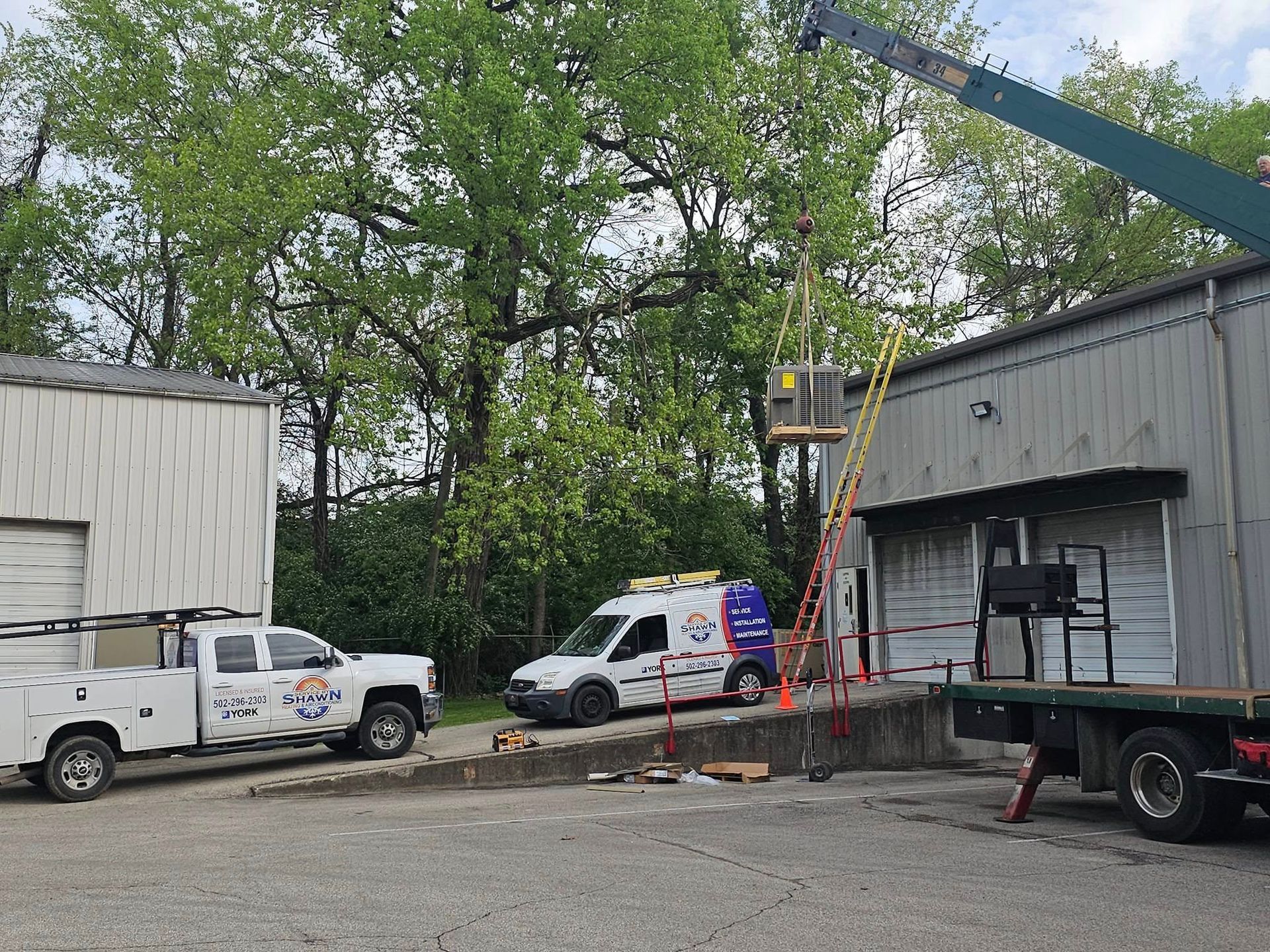 Two trucks and a crane are parked in front of a building.