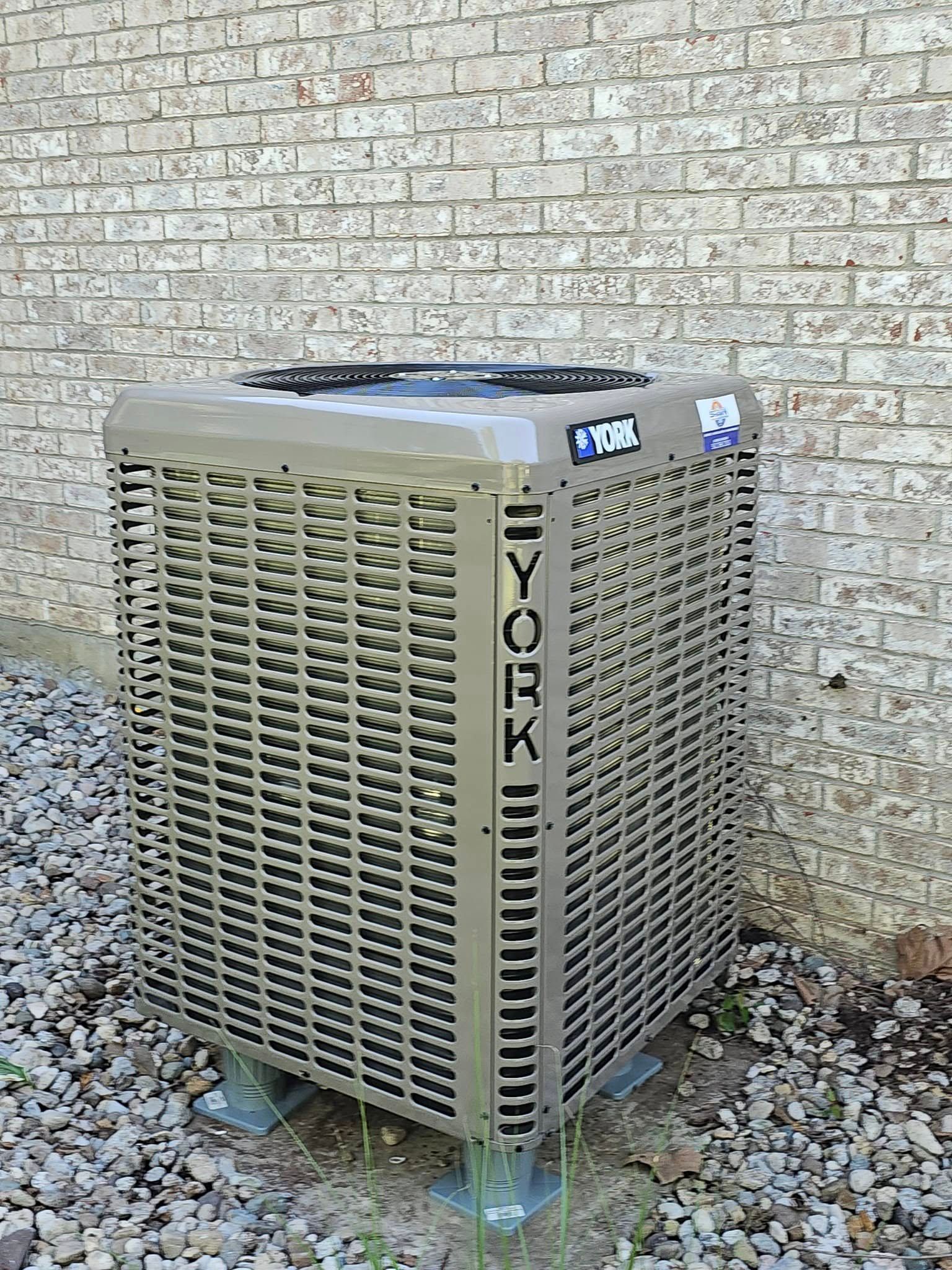 A york air conditioner is sitting outside of a brick building.