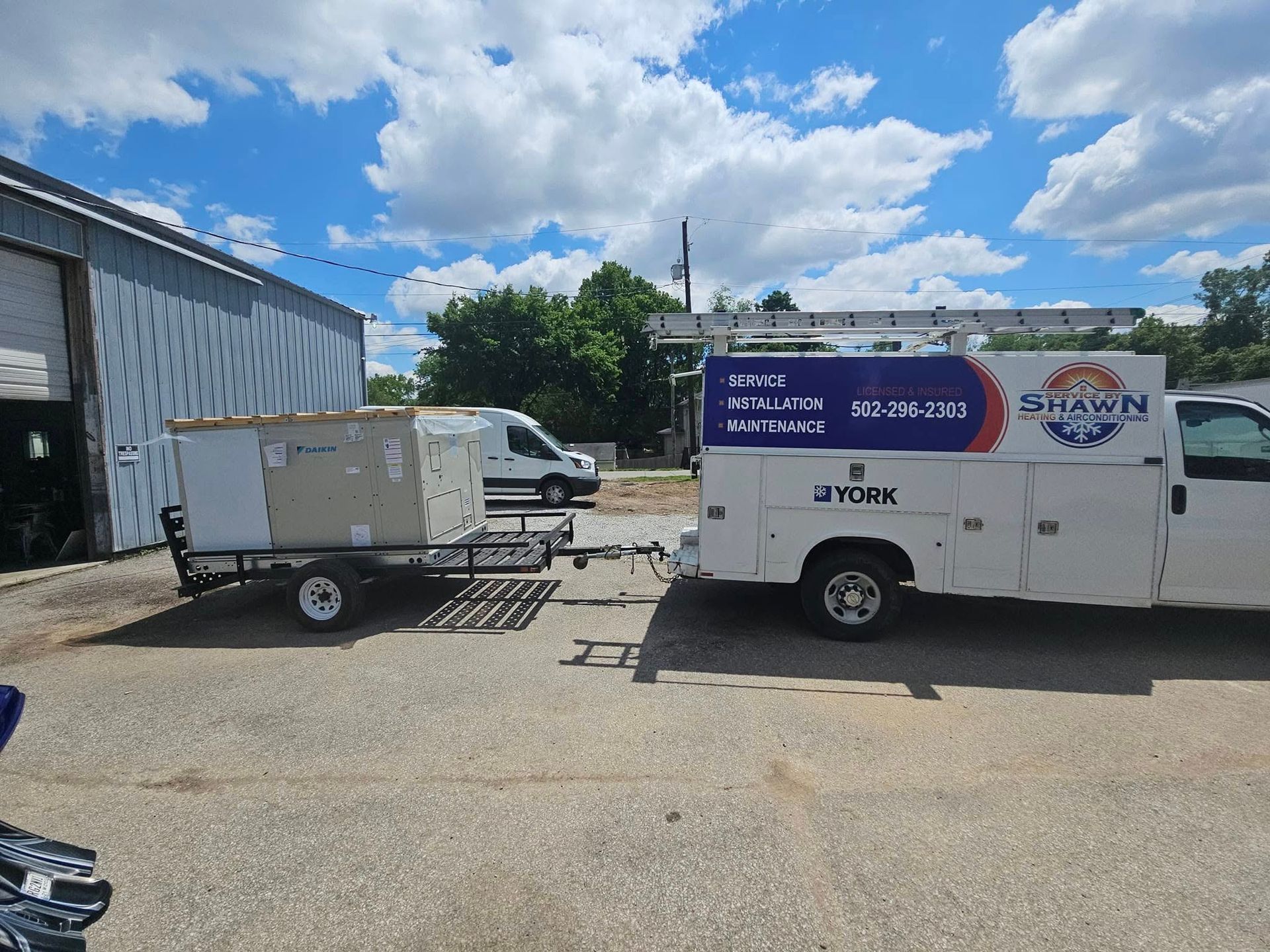 A white van with a trailer attached to it is parked in a parking lot.