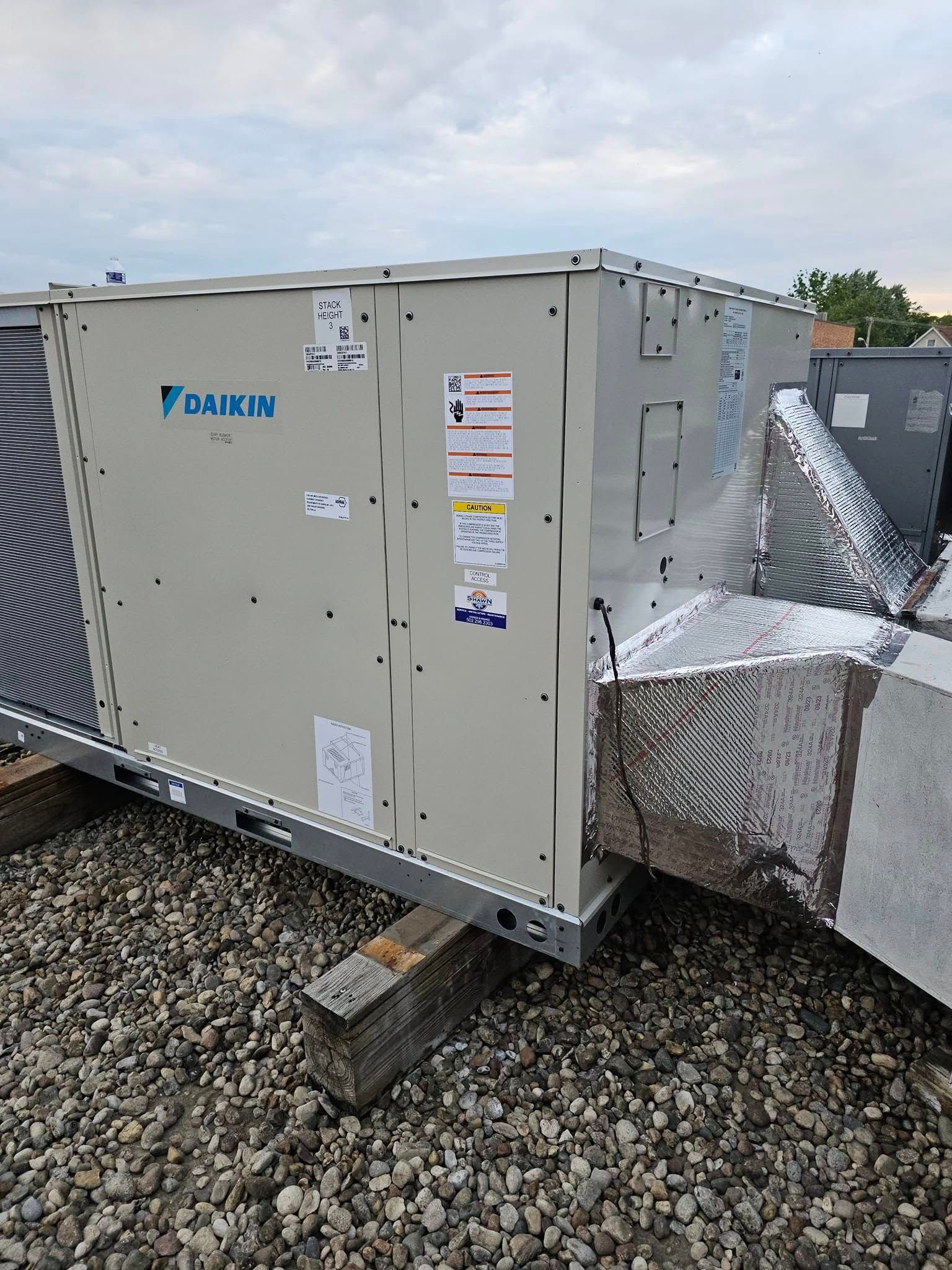 A large air conditioner is sitting on top of a pile of rocks.
