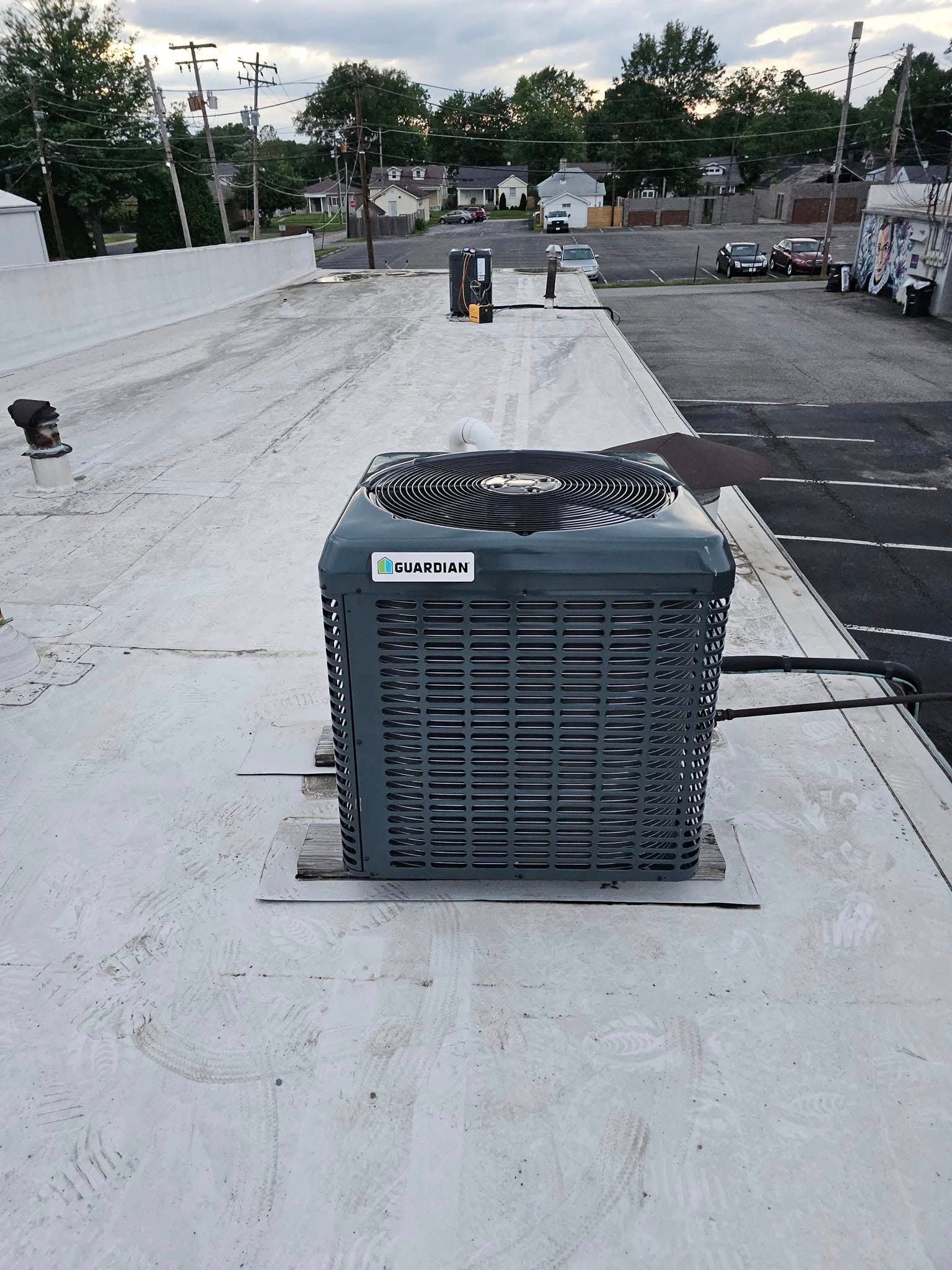 A large air conditioner is sitting on top of a white roof.