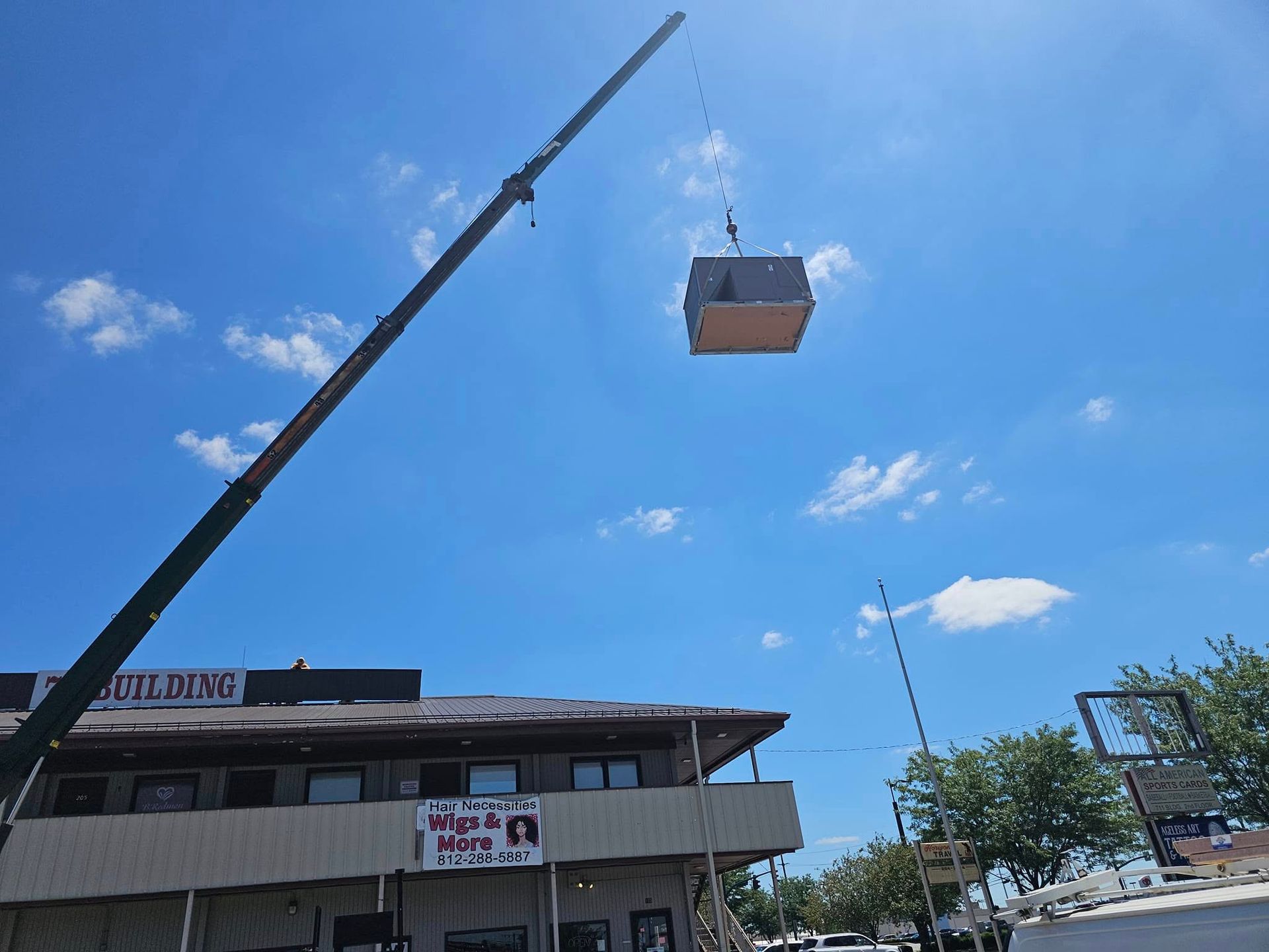 A crane is lifting a box in the air over a building.