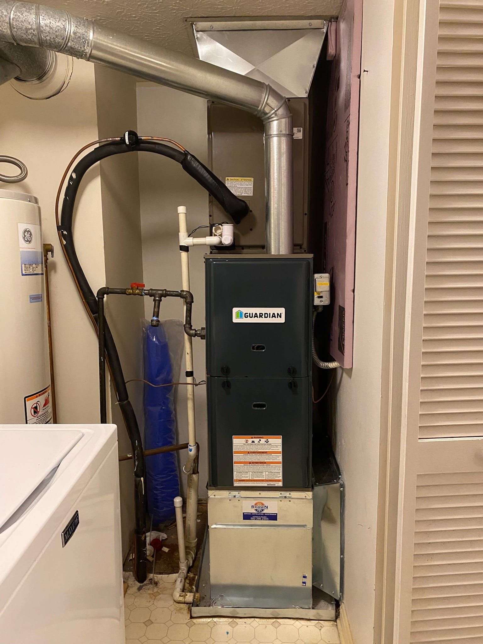 An air conditioner is sitting in a laundry room next to a washer and dryer.