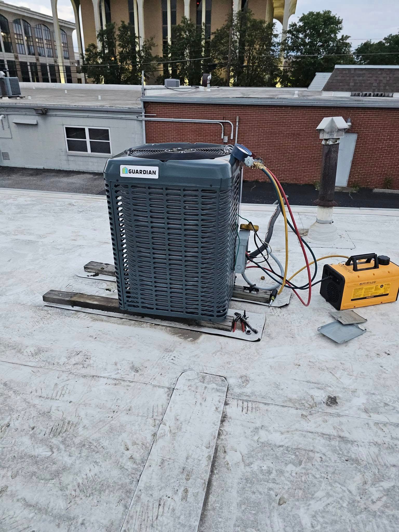 An air conditioner is sitting on top of a white roof.