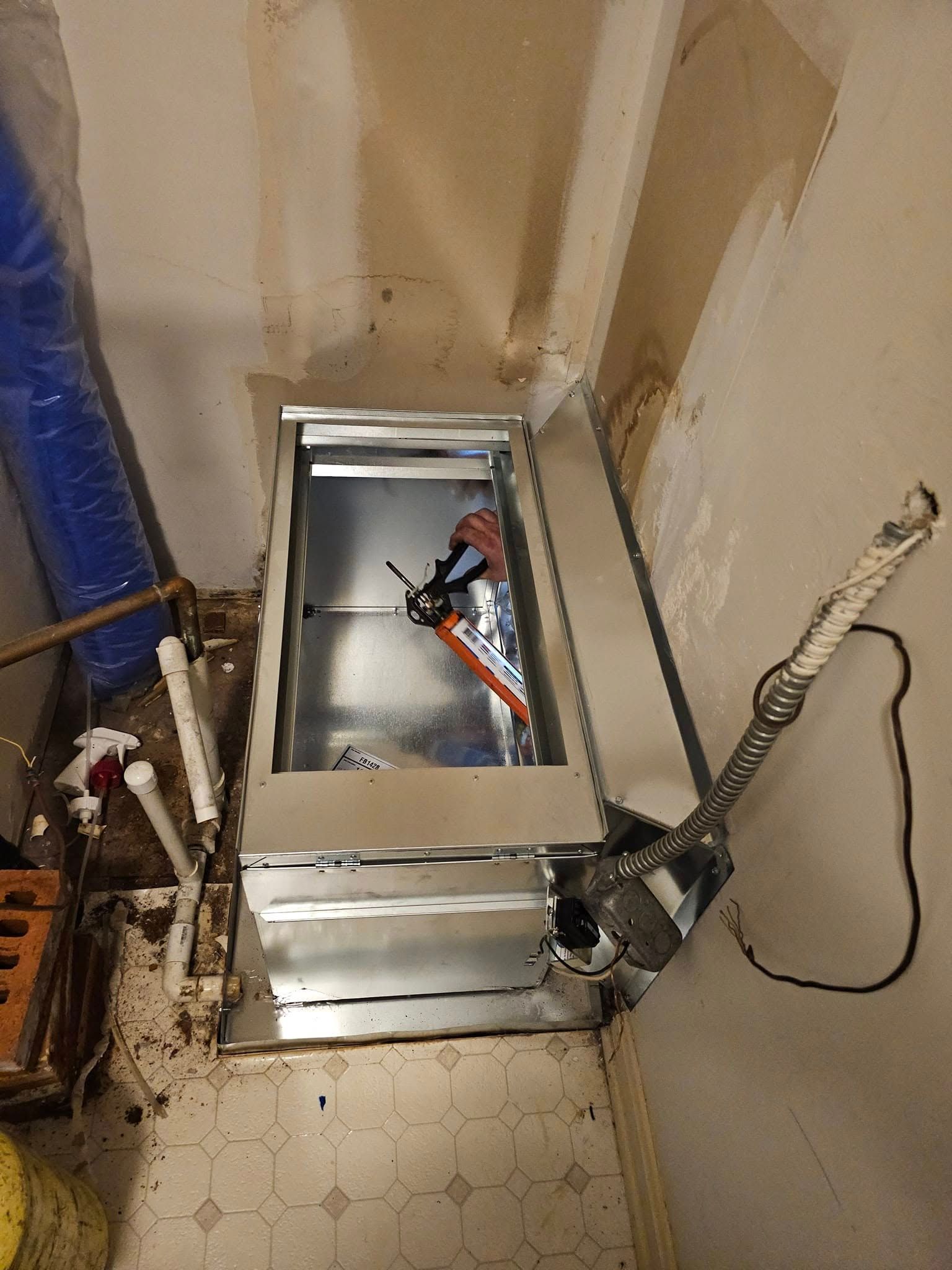 A metal box is sitting on the floor in a room next to a wall.