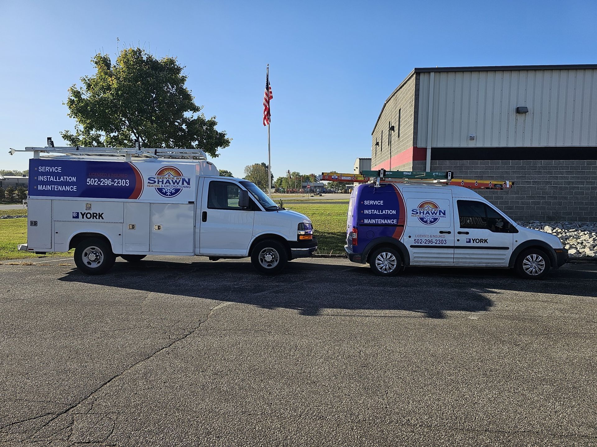 Two white vans are parked next to each other in a parking lot.