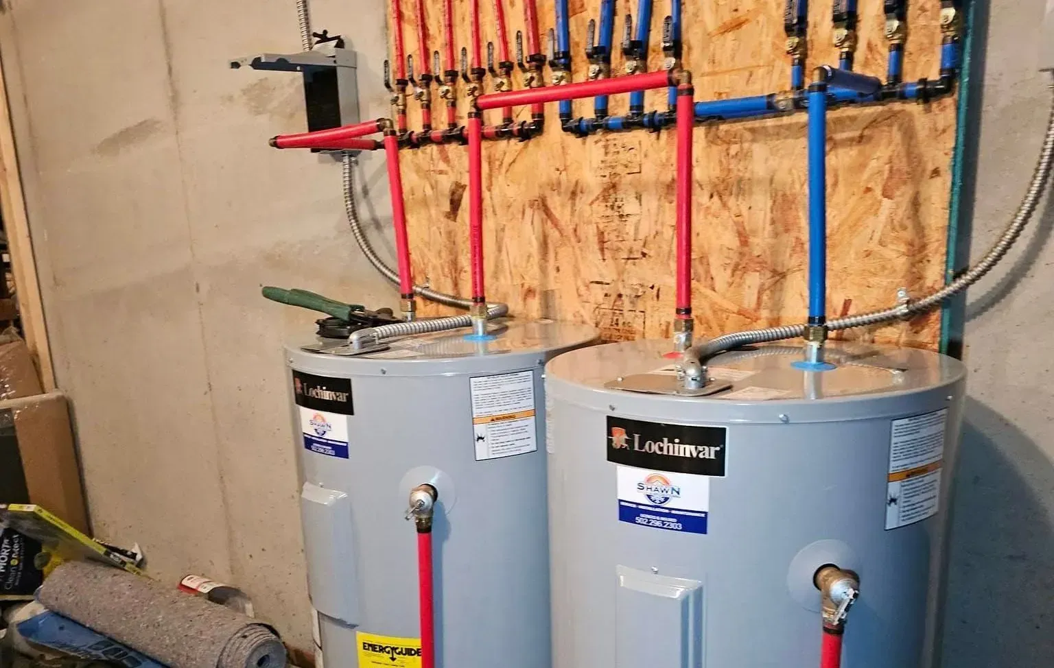 Two water heaters are sitting next to each other in a basement.
