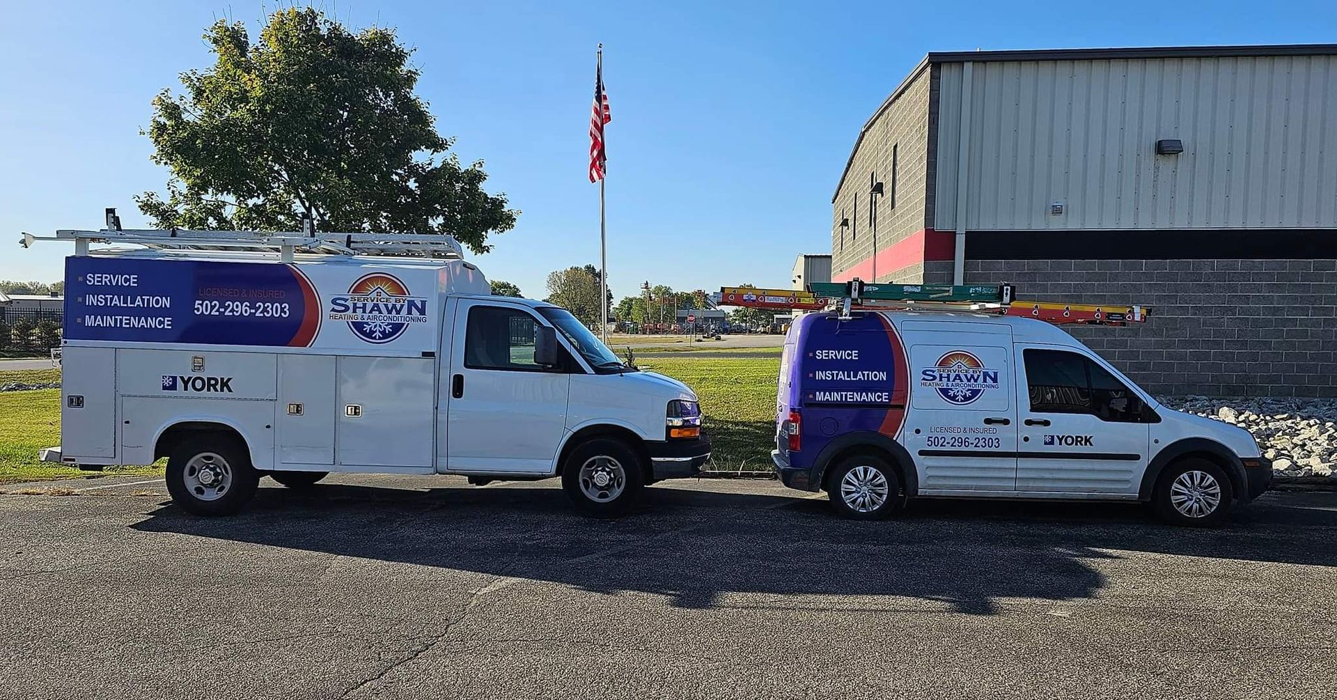 Two vans are parked next to each other in front of a building.
