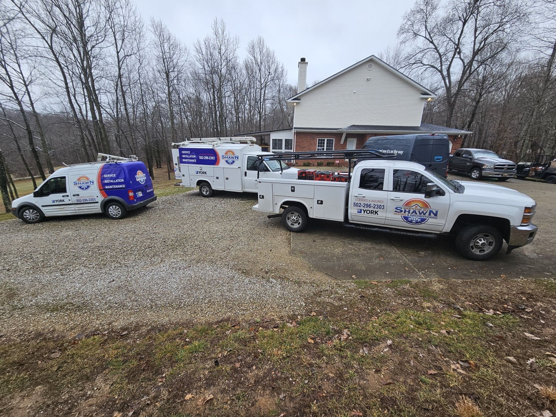 Three trucks and a van are parked in front of a house.