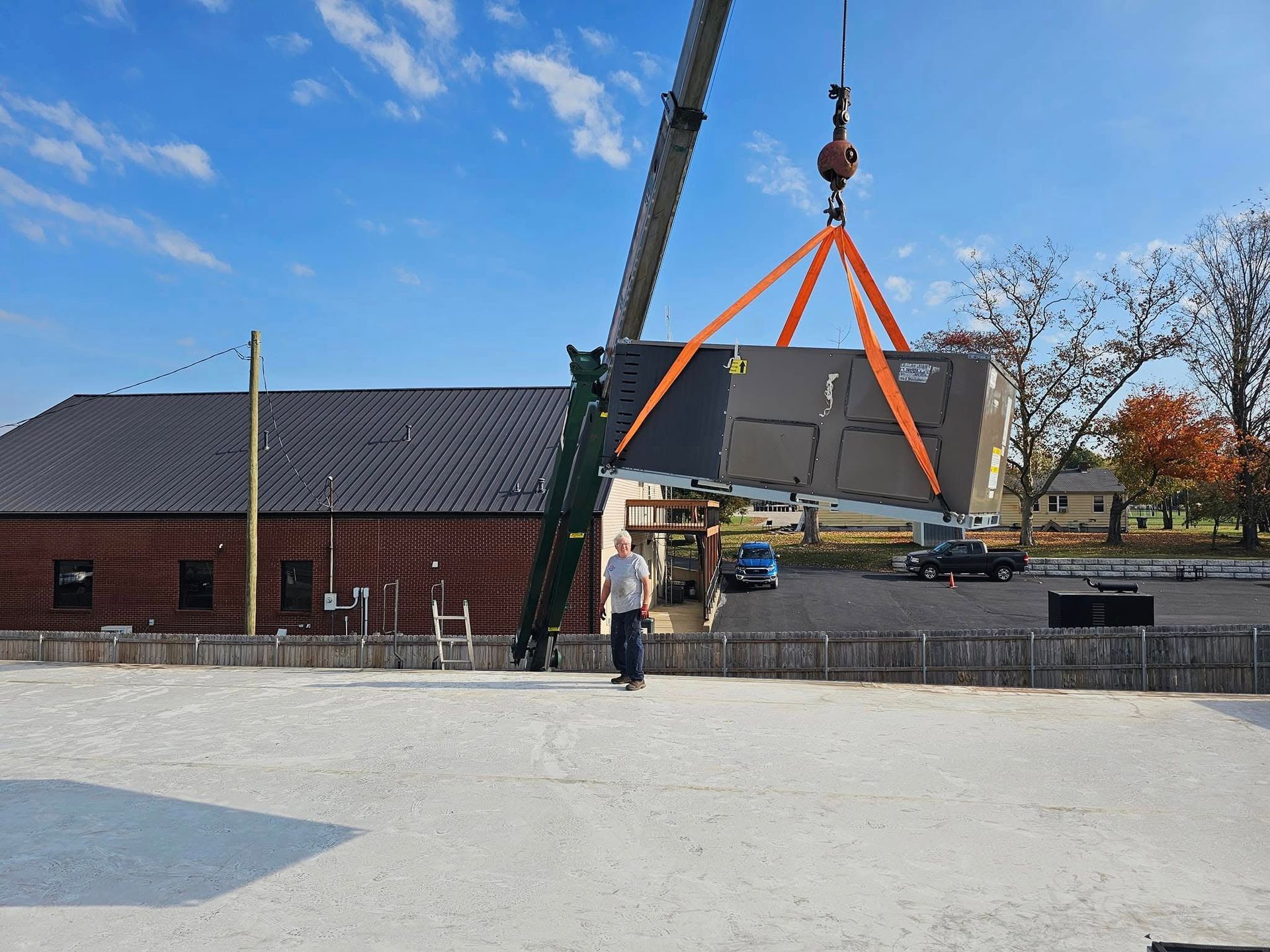 A crane is lifting a large piece of metal in front of a brick building