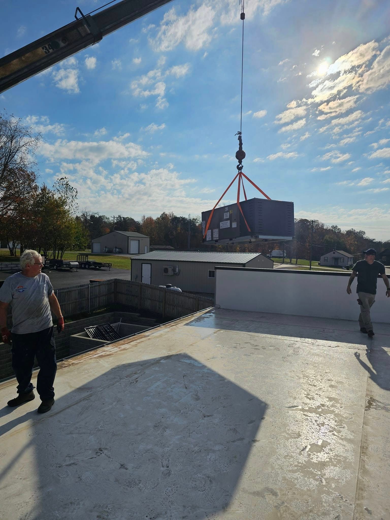 A man is standing on a roof next to a crane.