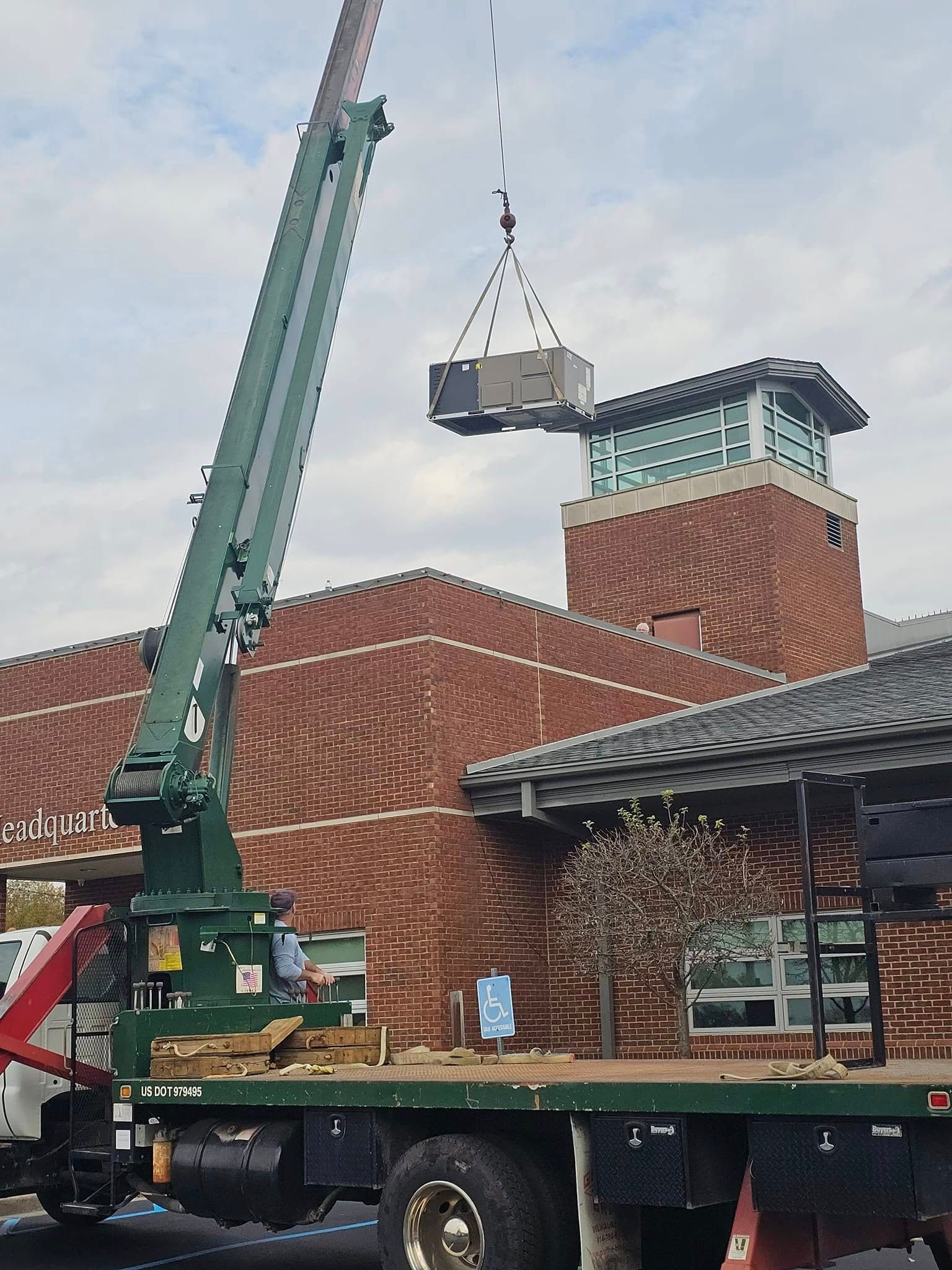 A crane is lifting a box from the back of a truck