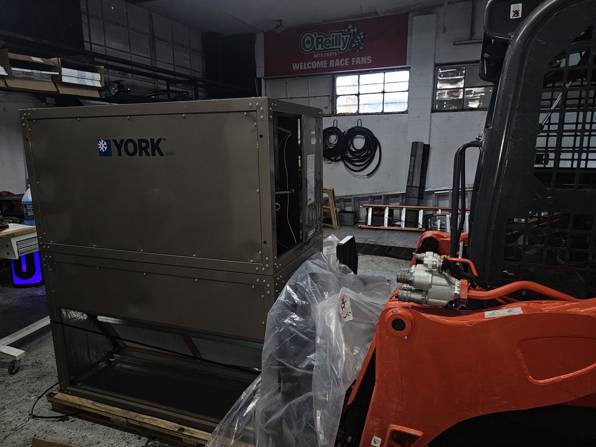 A forklift is sitting next to a york box in a garage.