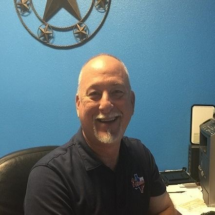 A man with a beard is smiling in front of a blue wall