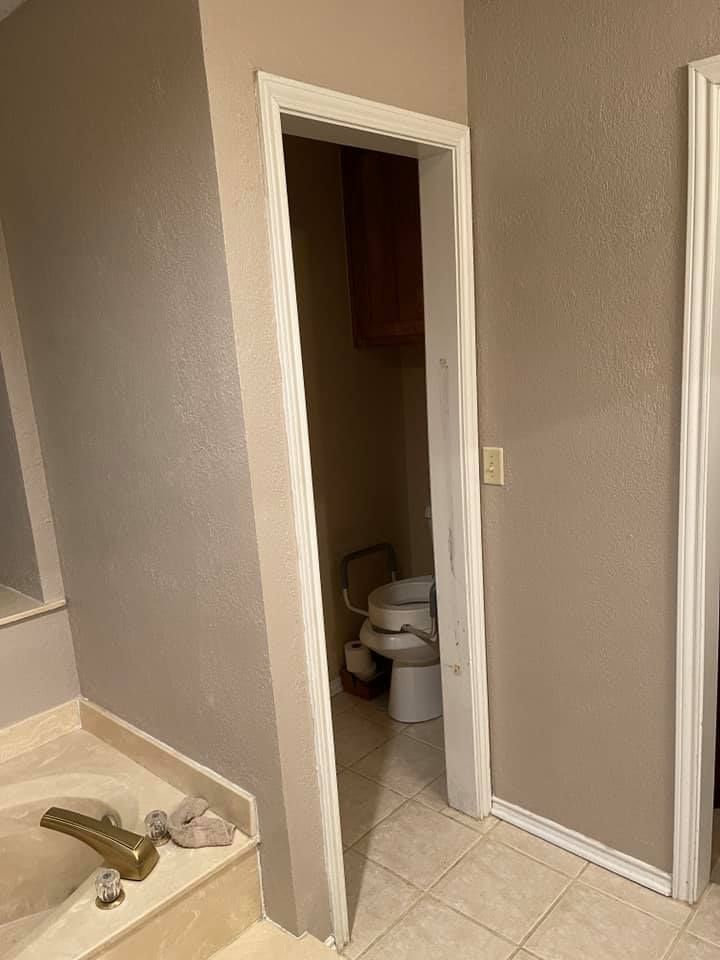 Bathroom doorway, white trim, open to a toilet, beige walls and tile floor.