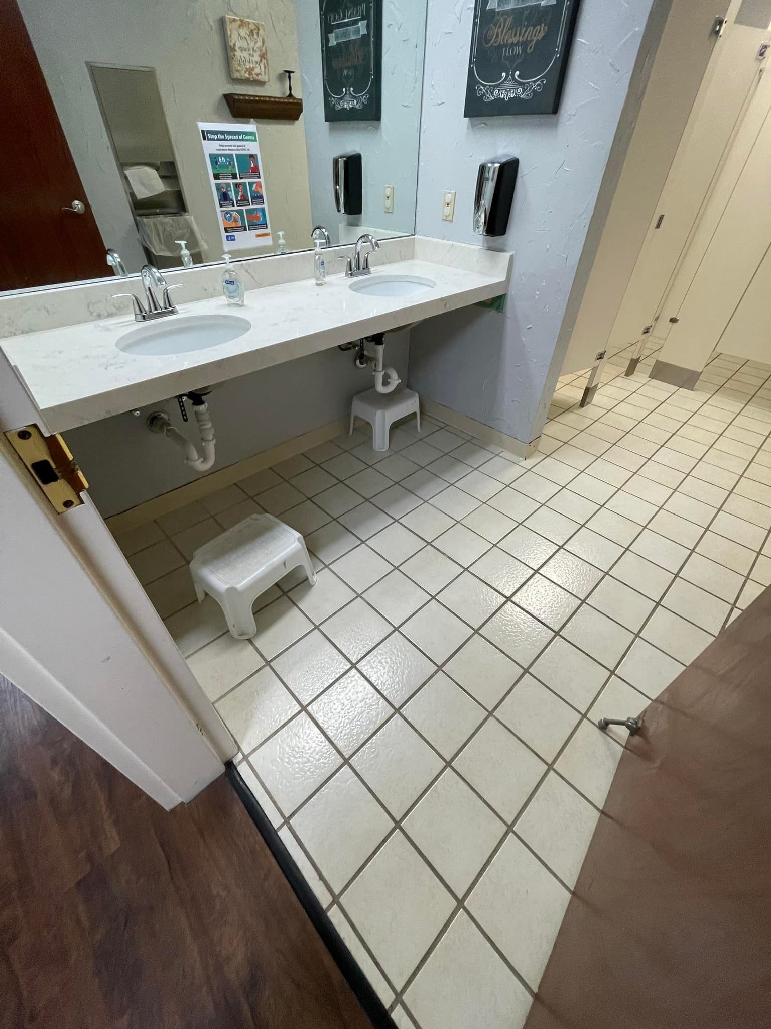 Bathroom with a sink counter, two stools, and tiled floor.
