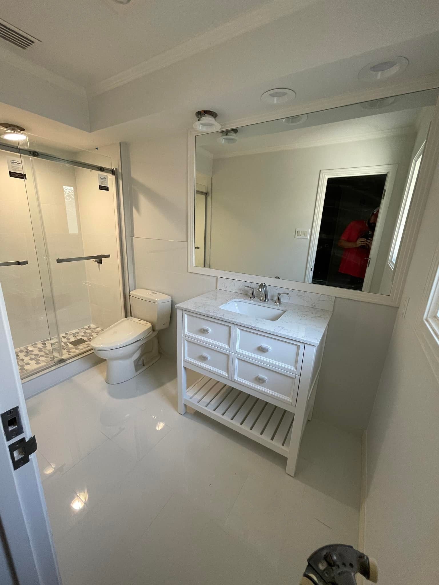 White bathroom with a vanity, toilet, and shower.