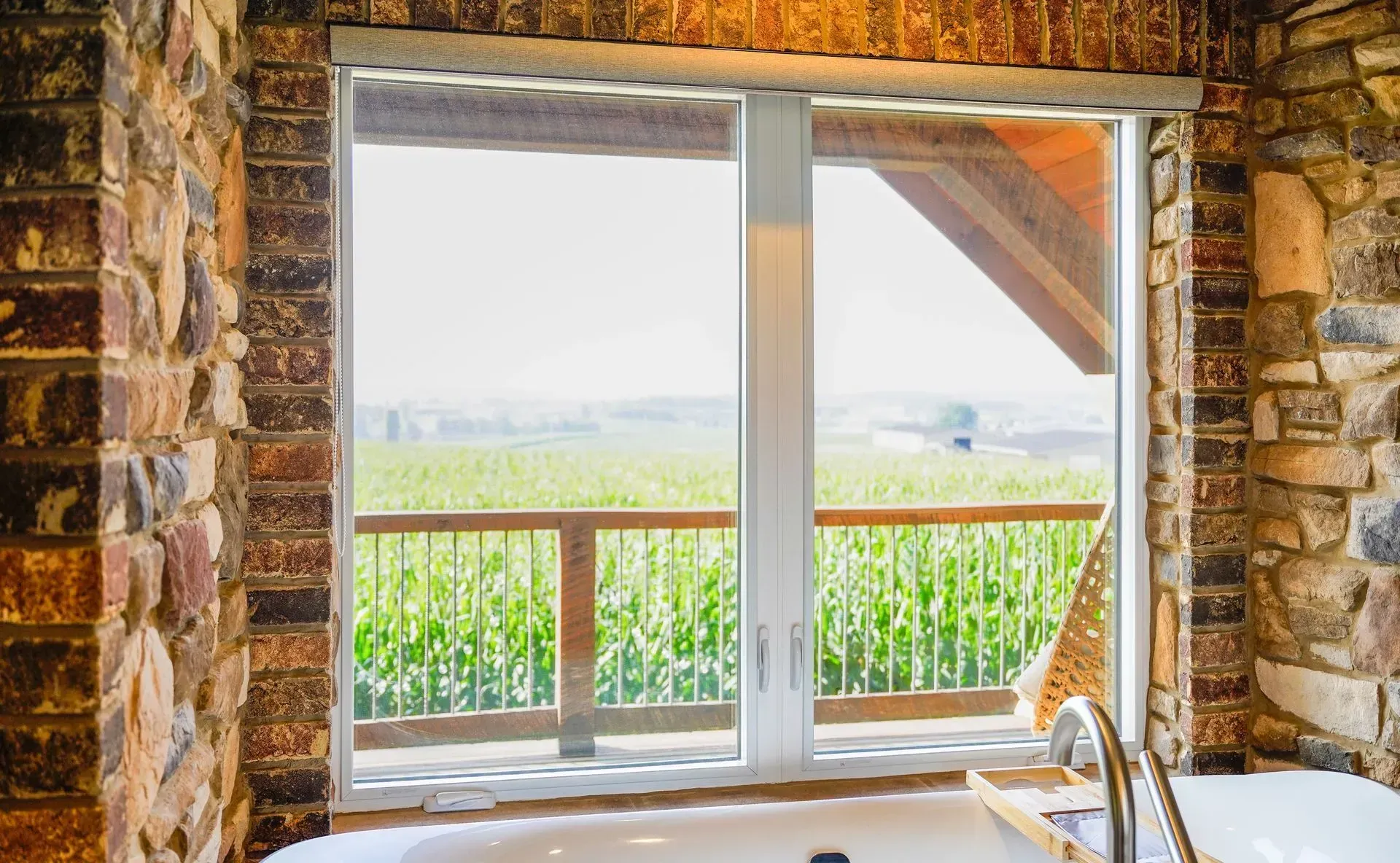 A porch with a white window and a black railing.