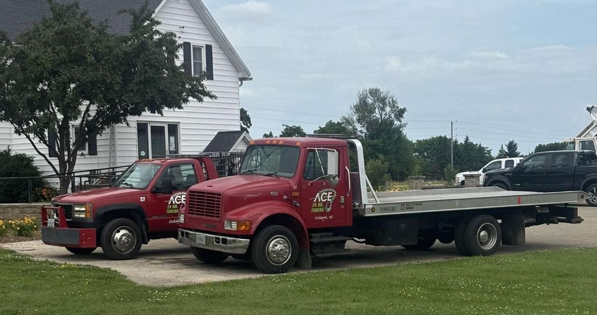 Red tow trucks parked outside a white house on a grassy lawn.