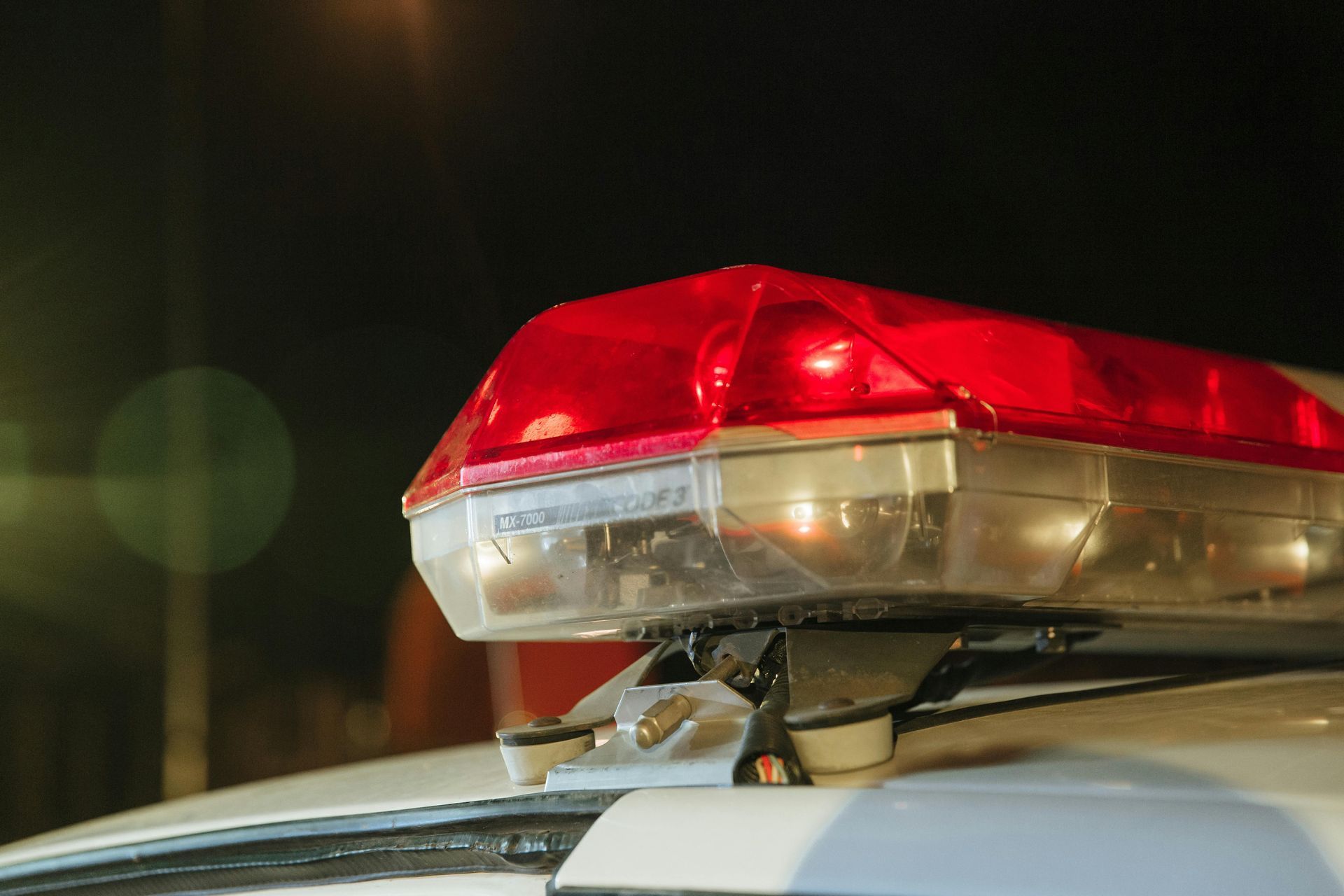 Close-up of a red and white police car light bar flashing at night.