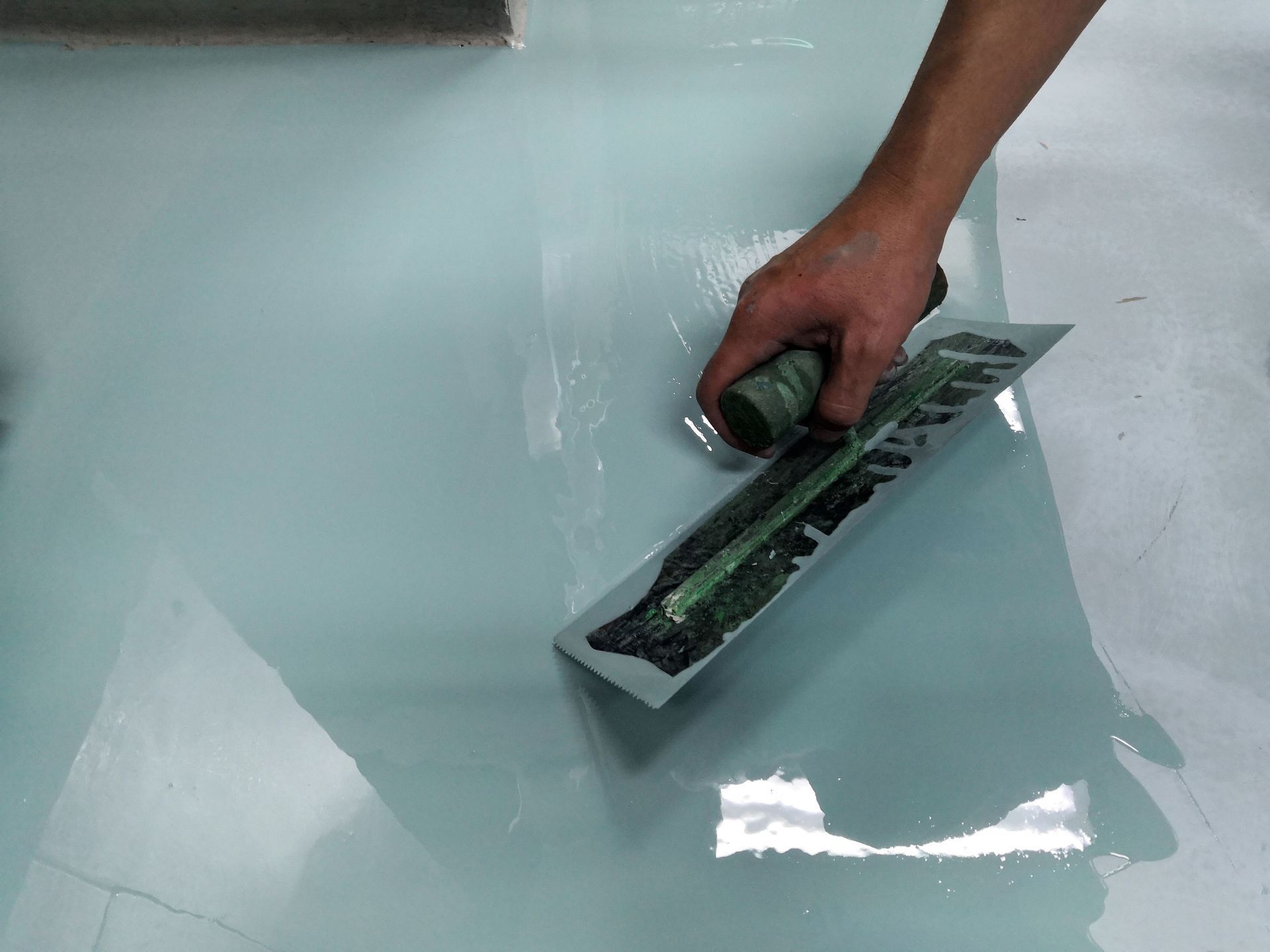 A person is using a trowel on a white floor
