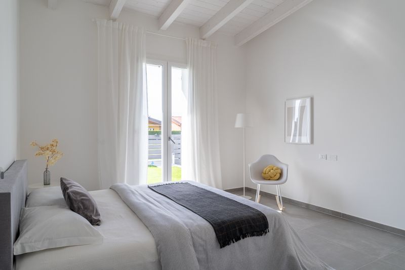 Una camera da letto con un letto, una sedia, una lampada e una finestra.