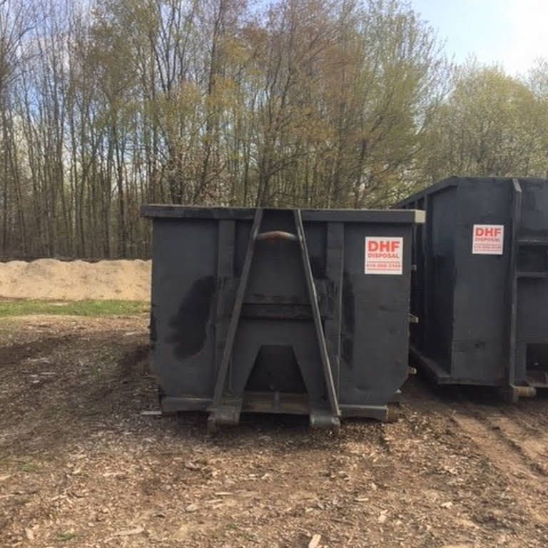Two dark gray dumpsters outdoors with 
