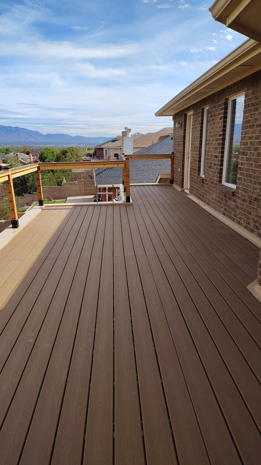 Brown composite deck with wood railing, overlooking a mountain landscape.