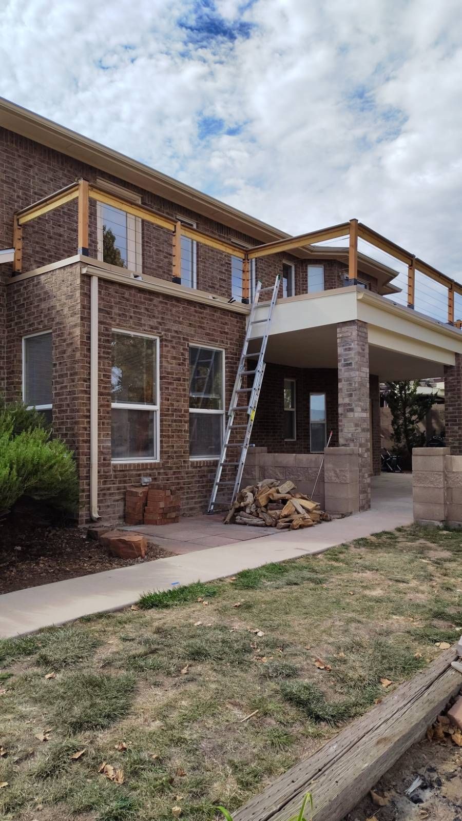 Brick house with a wooden deck being built; ladder propped against it.