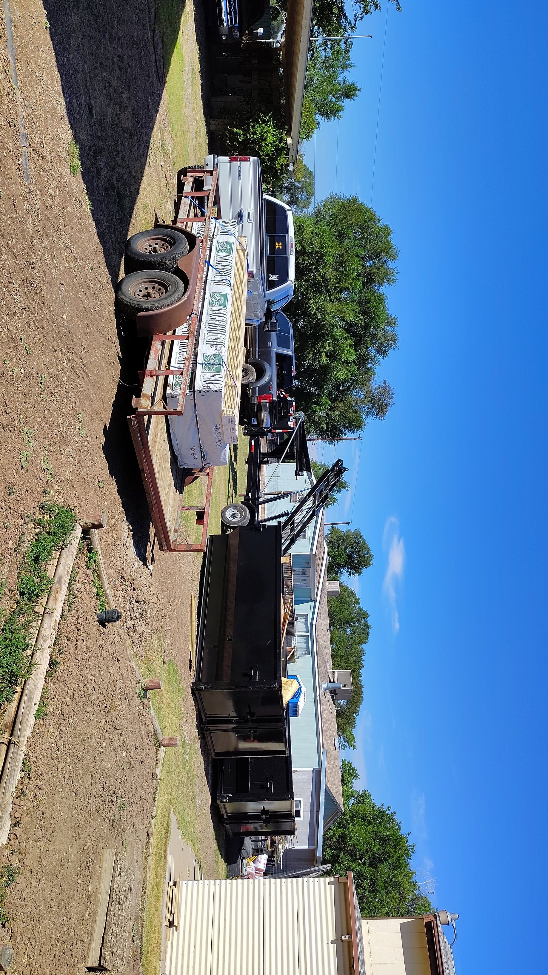 Trailer loaded with items parked outside under a bright blue sky.
