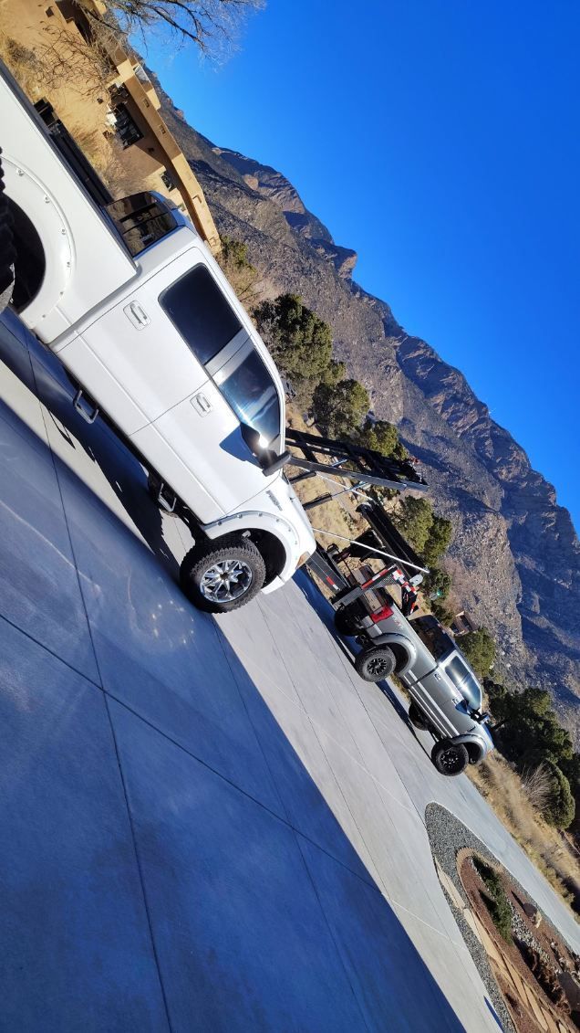 White pickup truck parked on driveway with mountain background. Sunny day.