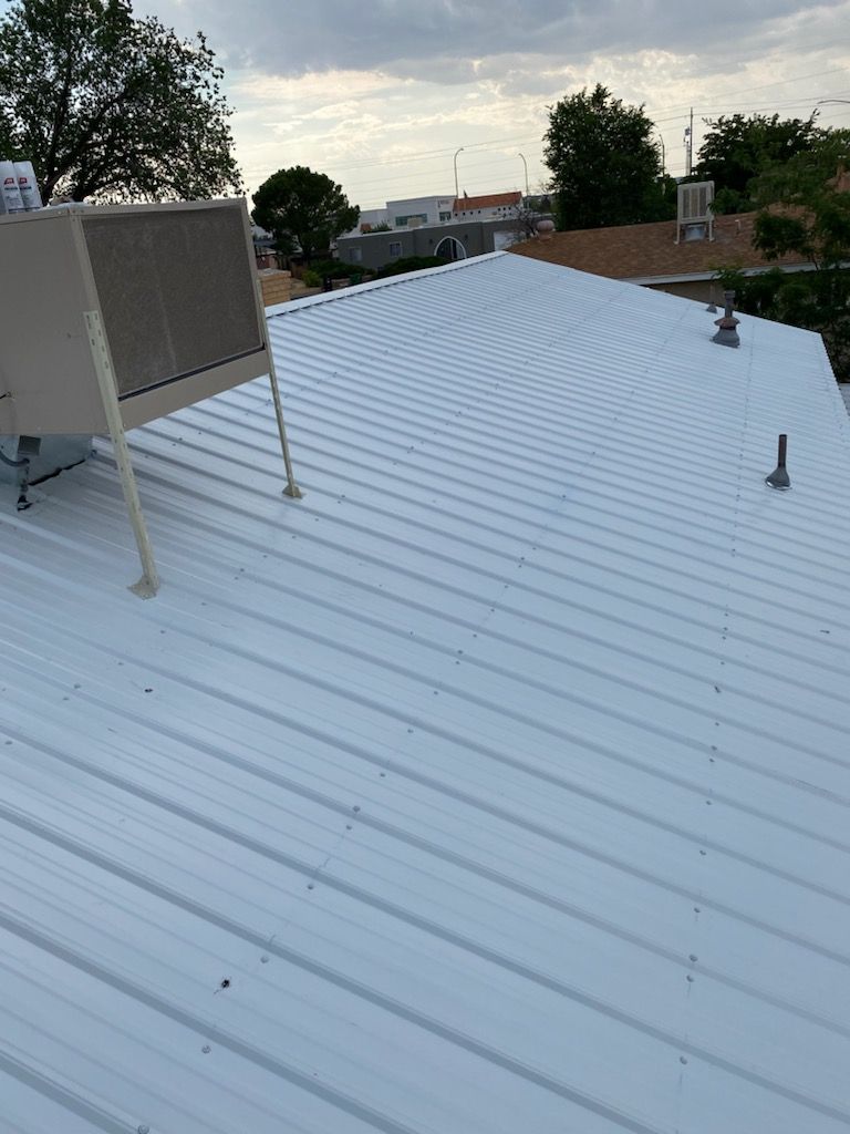 White corrugated metal roof with an air conditioning unit on a cloudy day.