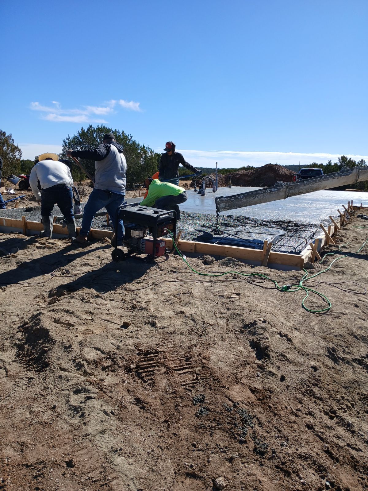 Construction workers pouring concrete foundation on a sunny day.