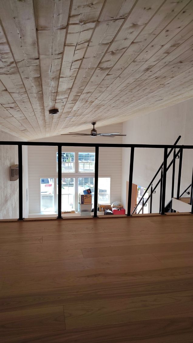 Interior with wood ceiling, glass and black metal railing, stairs, and windows to the exterior.