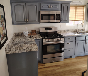 Kitchen with gray cabinets, stainless steel appliances, granite countertops, and wood floors.