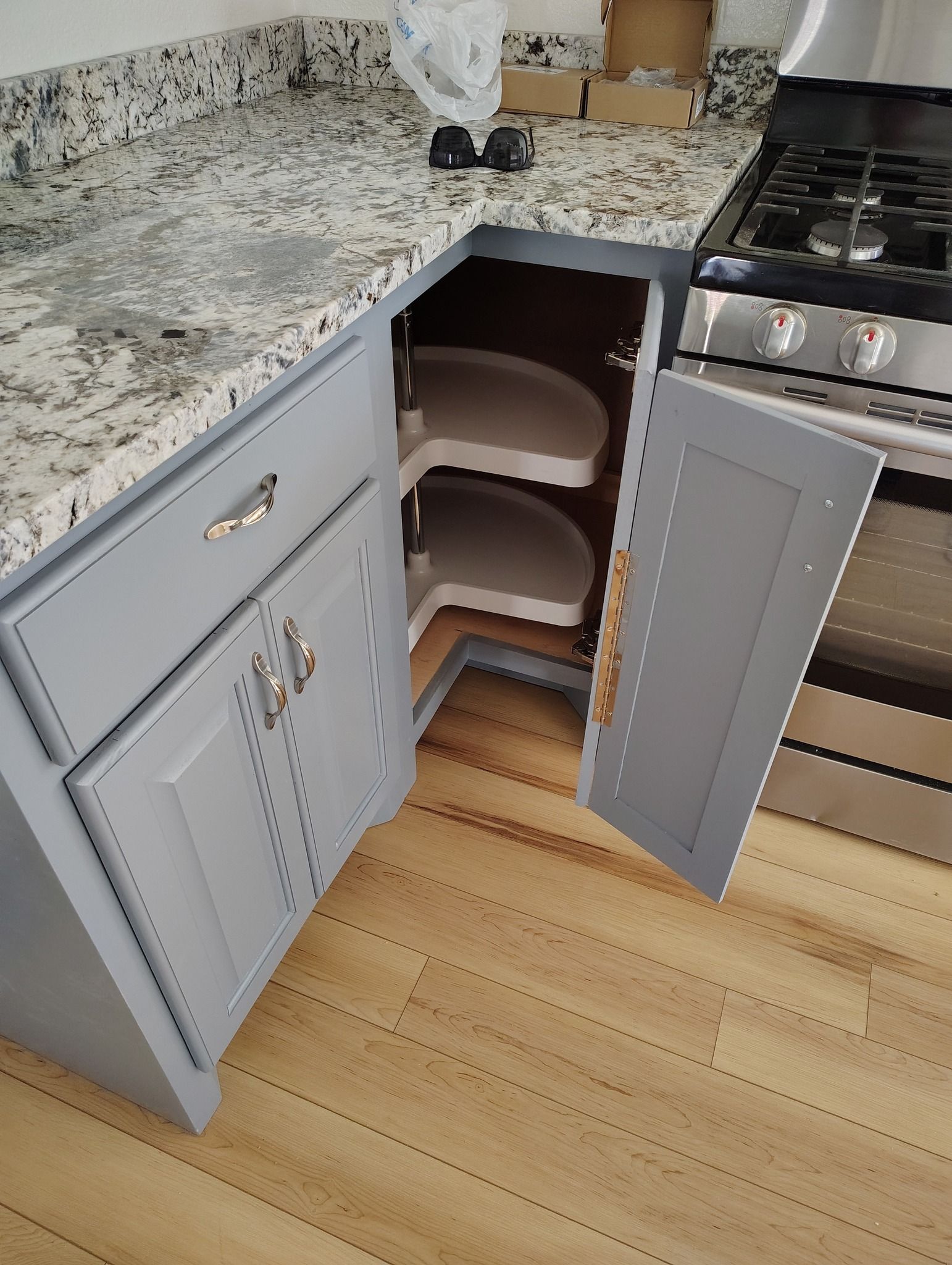 Gray kitchen cabinets with a lazy susan, granite countertop, and a gas range.