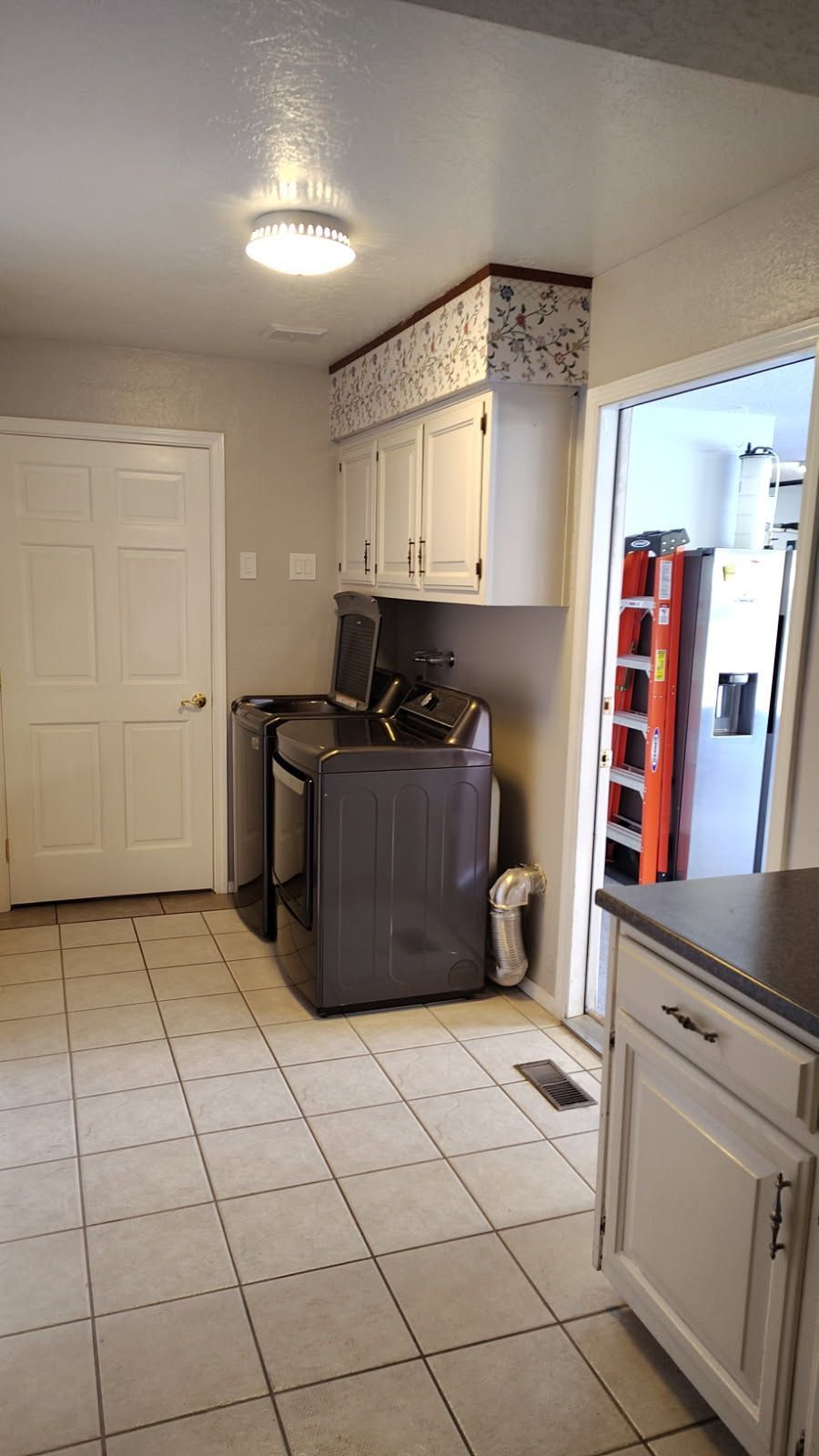 Interior view of a room with terracotta tile flooring, windows, and a high, slatted wooden ceiling. Sunlight streams in.