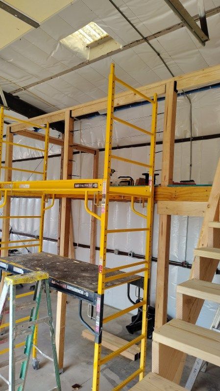 Yellow scaffolding inside a building; wooden frame construction visible.