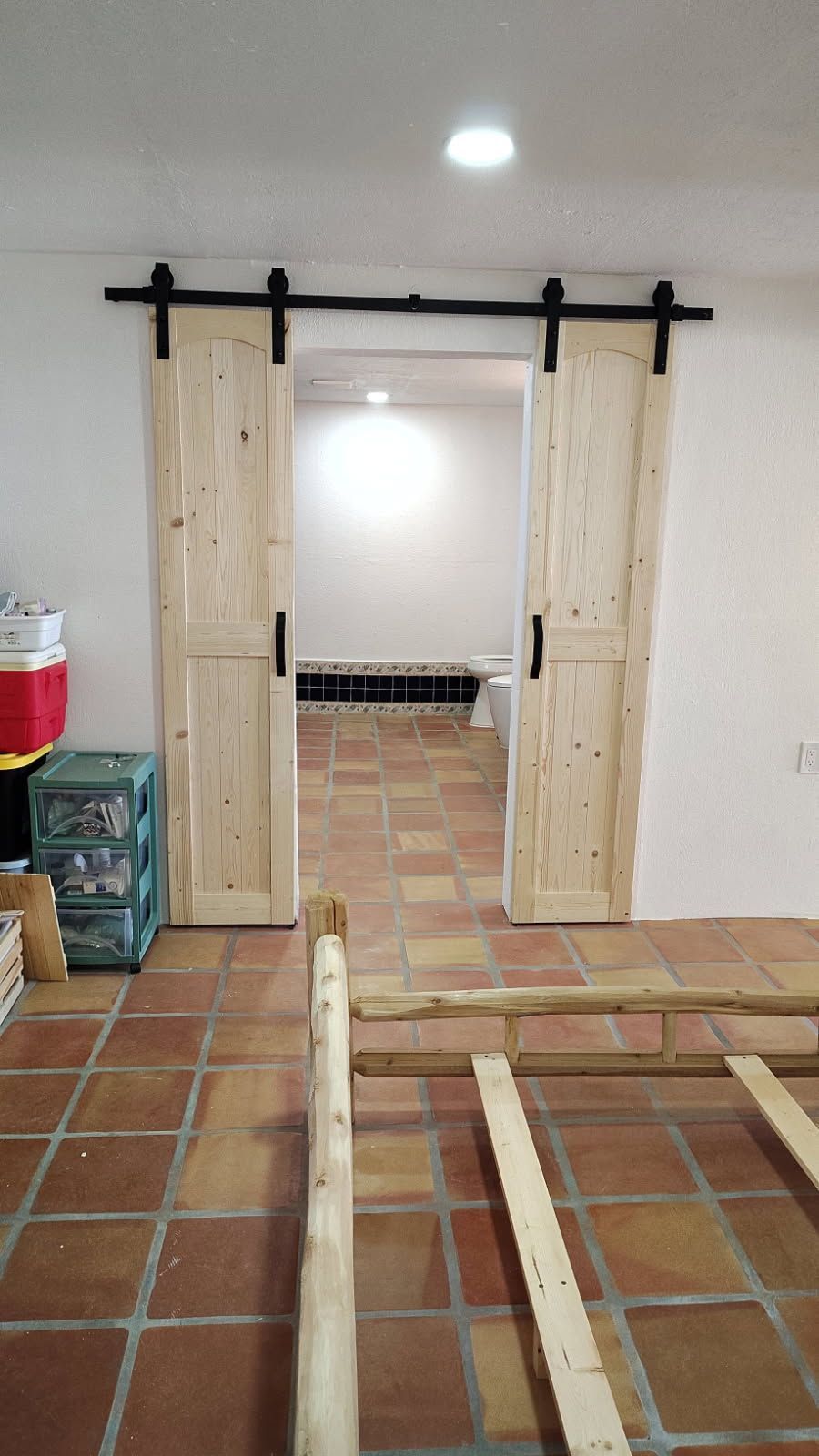 Barn doors on track, light wood, opening to a room with tiled floor.