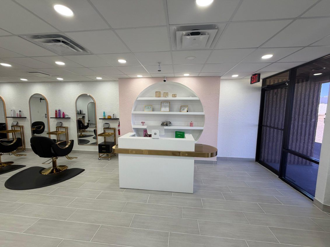 Interior view of a room with terracotta tile flooring, windows, and a high, slatted wooden ceiling. Sunlight streams in.