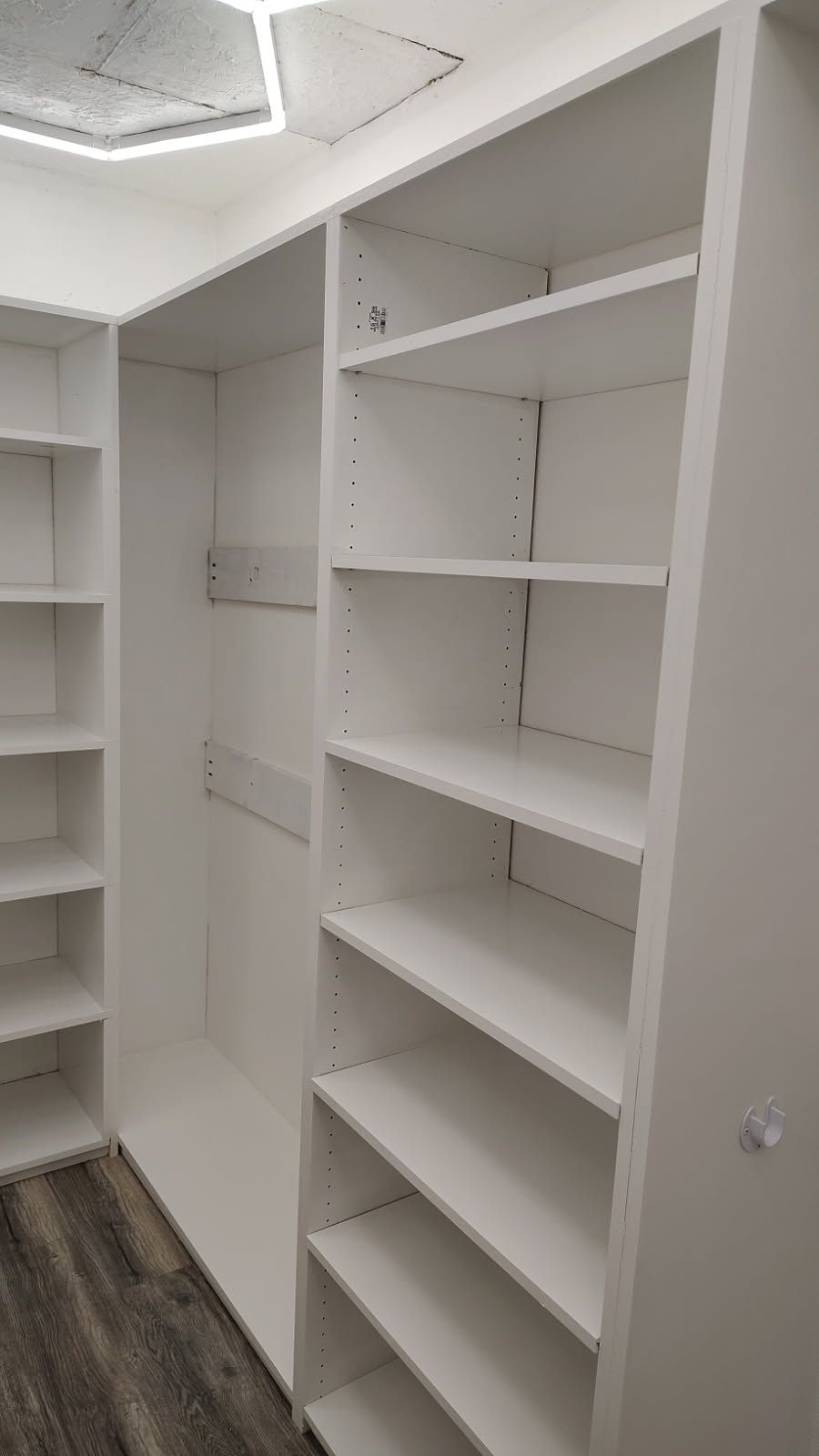 White built-in closet with shelves and hanging rod. Interior view of an empty closet space.