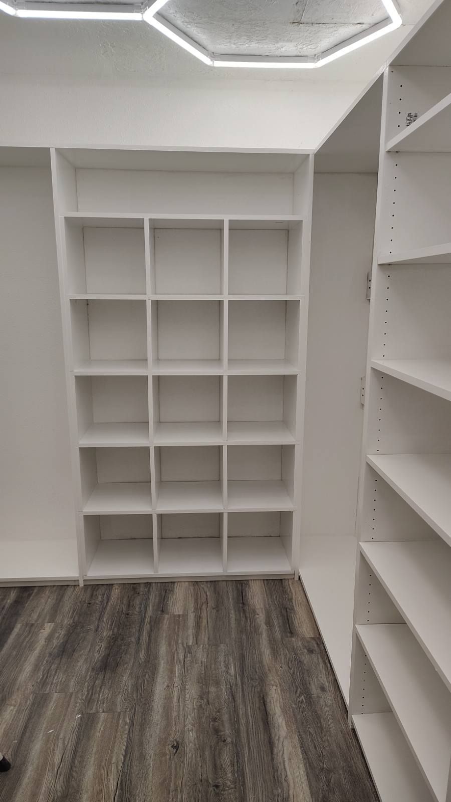 White built-in shelving unit with multiple cubbies on a wall with wood-look flooring.