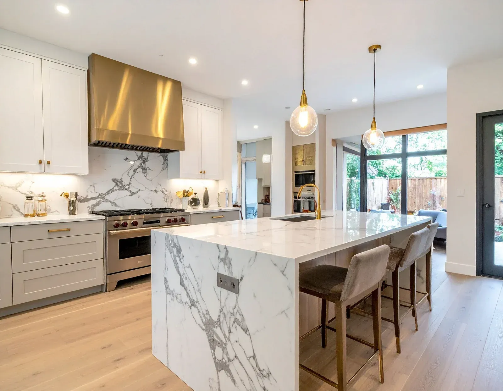 Modern kitchen with marble island, gold accents, and bar stools.