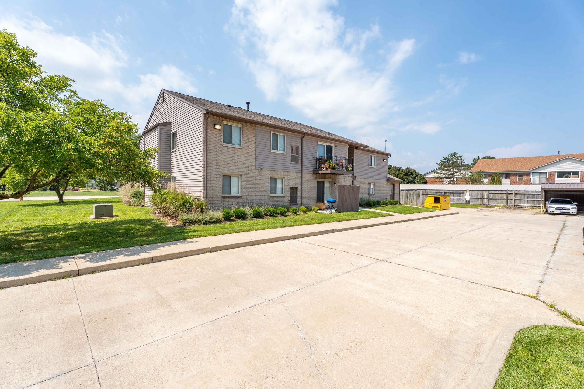 Two-story brick building with parking lot in front on a sunny day.