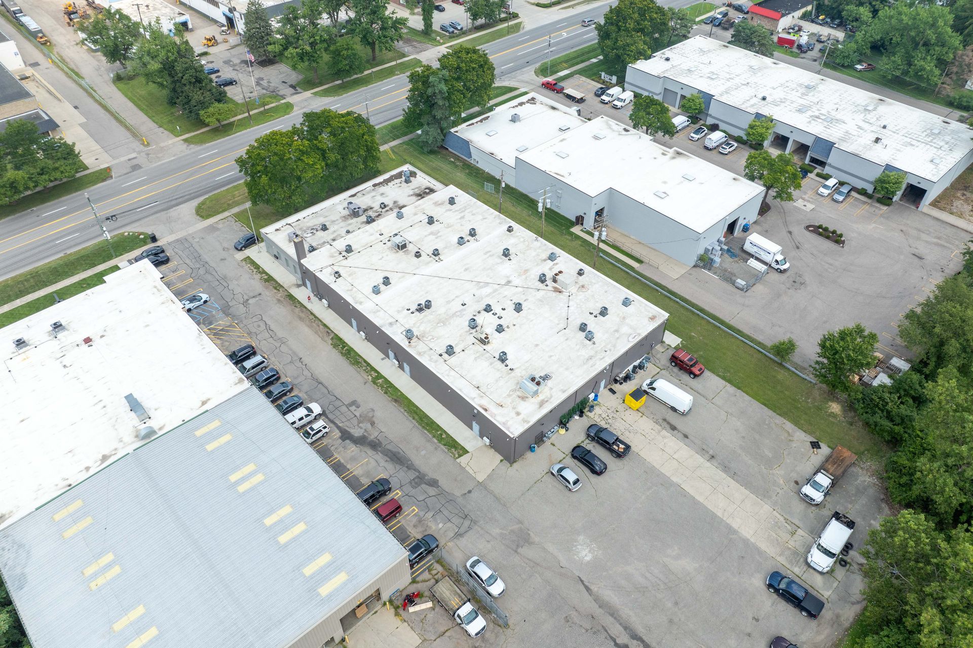 Aerial view of industrial buildings with trucks and cars in parking areas.