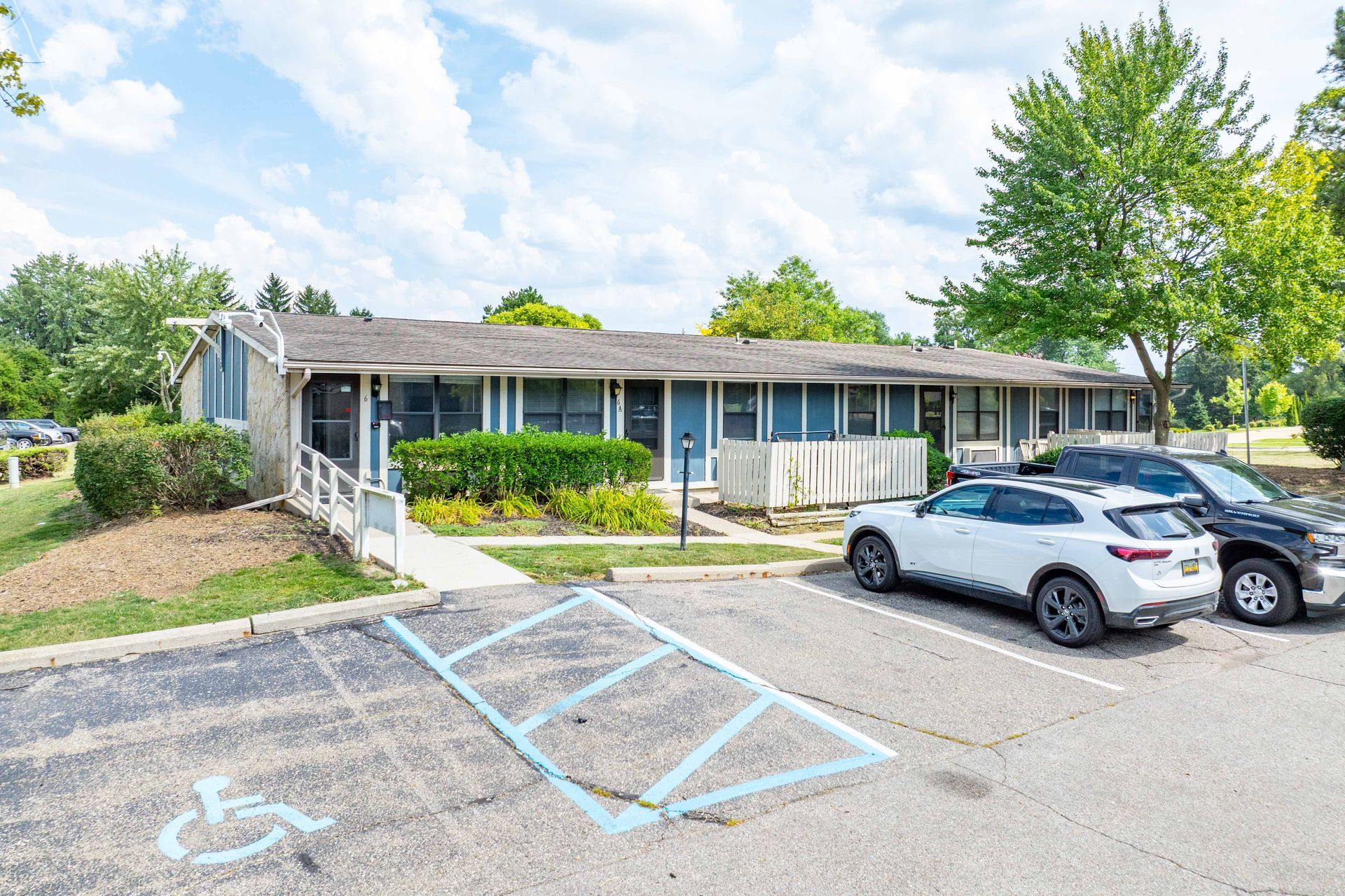 A low, one-story apartment building with a wheelchair ramp and accessible parking spot.