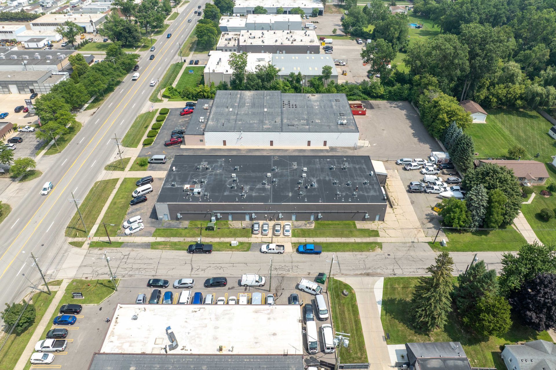 Aerial view of industrial buildings, parking lots, and a road with cars.