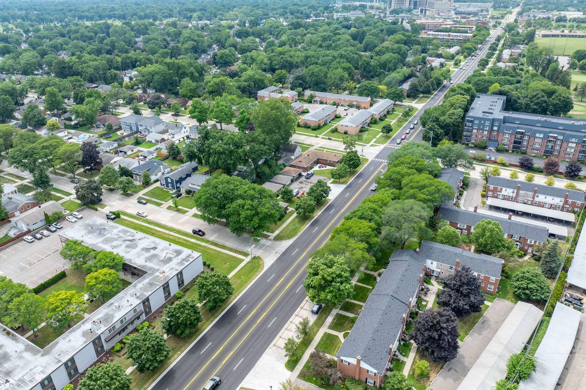 Aerial view of a tree-lined street with houses and apartment buildings on either side.