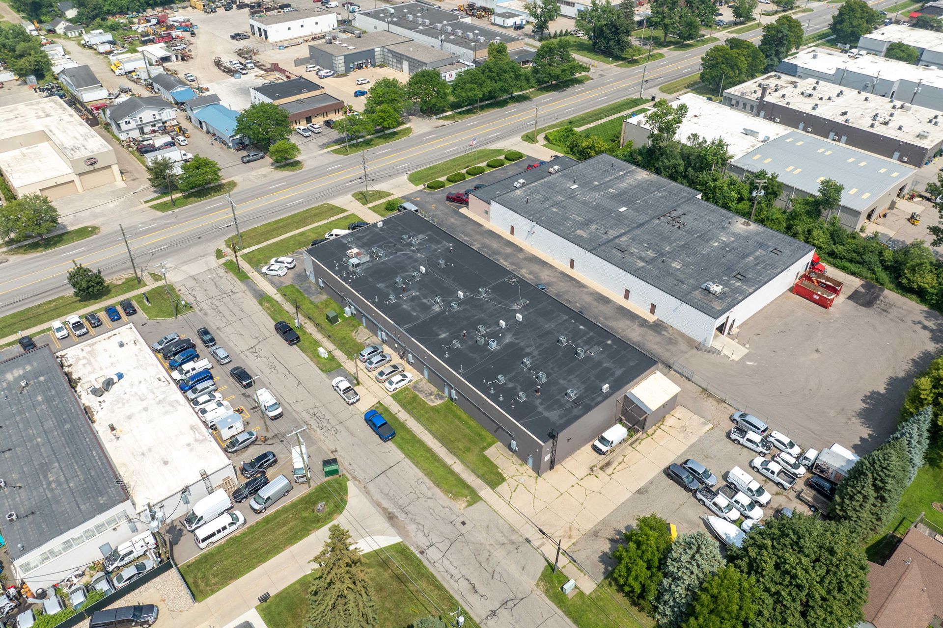 Aerial view of industrial buildings, a street, and parking lots.